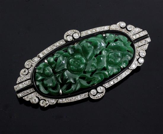 A 1920s/1930s Art Deco white gold?, pierced carved jadeite, diamond and black onyx set oval brooch, 53mm.